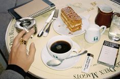 a table topped with a cup of coffee and a slice of cake on top of it