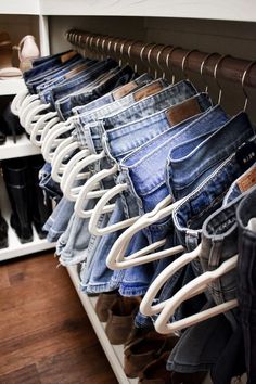 several pairs of jeans are hanging in a closet