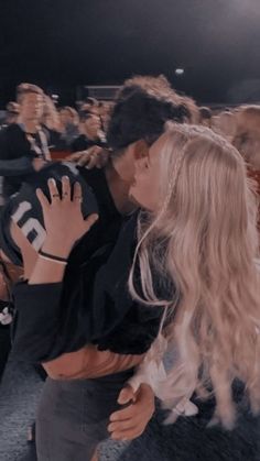 a woman kissing a man in the middle of a crowd