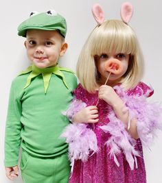 two children dressed in costumes standing next to each other, one holding a lollipop