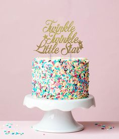 a cake decorated with sprinkles and the words oh baby on top is sitting on a pedestal