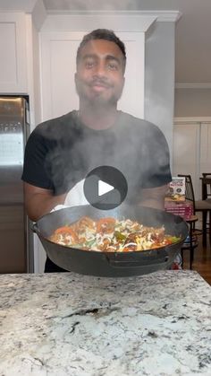 a man standing in front of a frying pan filled with food