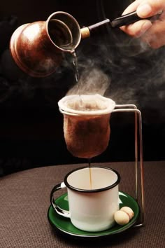 a person pouring coffee into a cup on top of a green saucer and plate