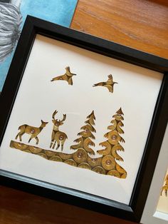 two framed pictures with deer and birds in the woods, one is gold on white