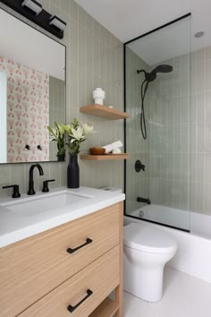 a white toilet sitting next to a bathroom sink under a mirror and a wooden cabinet