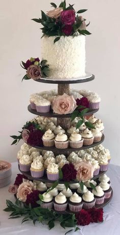 a three tiered cake with cupcakes and flowers on it