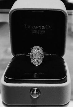 an engagement ring in a box with the words tiffany & co on it's side