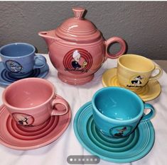 there are many different colored cups and saucers on the table