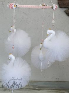 two white swan mobiles hanging from a pink and white string with flowers on them