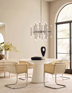 a dining room table with four chairs and a vase on the table in front of it