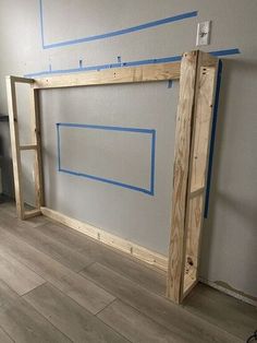 an unfinished room with blue tape on the wall and wood flooring in front of it