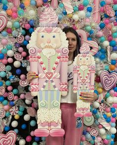 a woman standing in front of a wall covered with candy canes and candies