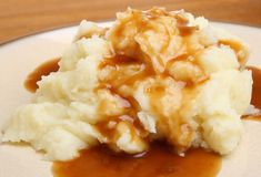 mashed potatoes covered in gravy on a white plate with caramel sauce