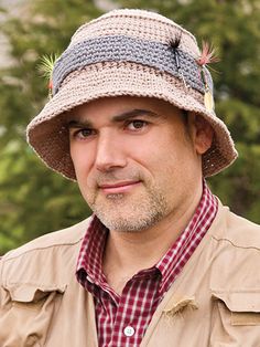 a man wearing a hat standing in front of trees