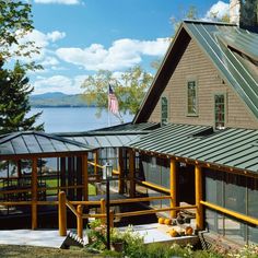 a house with a metal roof next to the water and trees in front of it