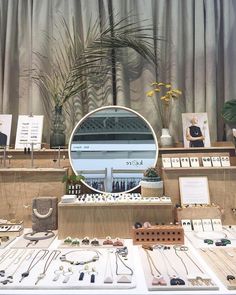 an assortment of necklaces on display in front of a round mirror with palm tree behind it