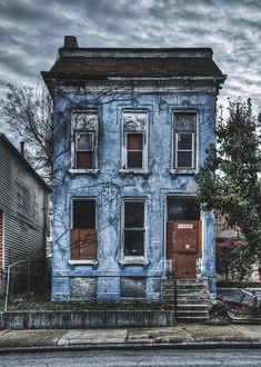 an old blue house with boarded up windows