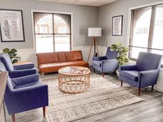 a living room with blue chairs and a coffee table in front of two large windows