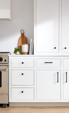 a stove top oven sitting inside of a kitchen next to white cupboards and drawers