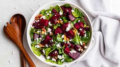 a salad with beets, feta cheese and walnuts in a white bowl