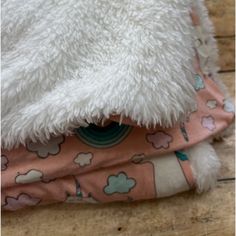 a white teddy bear laying on top of a bed next to a pink and blue blanket