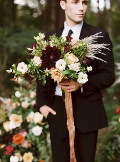 a man in a suit holding a bouquet of flowers