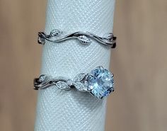 two rings on top of each other with an aqua blue stone in the middle and leaves around them