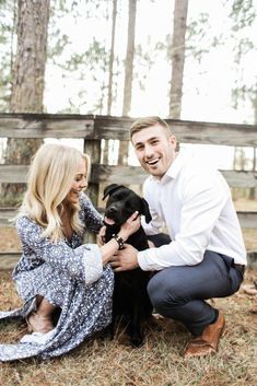 a man kneeling down next to a woman holding a black dog in front of them