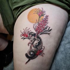 a woman's thigh with a koala and flowers tattoo design on her leg