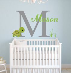 a white crib with a green turtle and the letter m on it