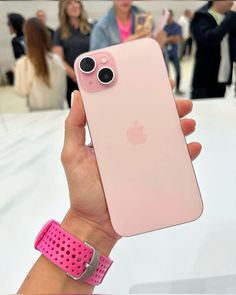 a person holding an iphone in their hand with pink bracelets on it's wrist