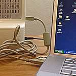 an open laptop computer sitting on top of a wooden desk next to a power strip