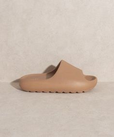 a pair of beige shoes sitting on top of a white floor next to a wall