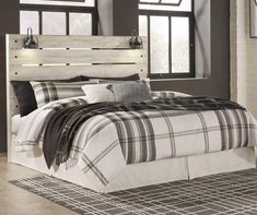 a bed with plaid sheets and pillows in a room