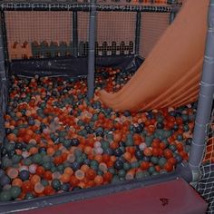 there are many balls in the ball pit and one is on top of an orange slide