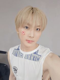 a young man wearing a white t - shirt with red spots on his face and arm