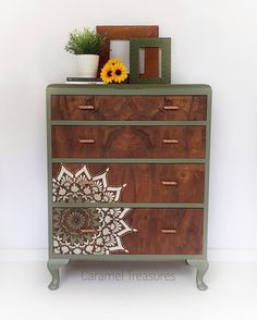 a wooden dresser with an intricate design painted on the front and sides, sitting against a white wall