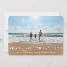 an image of a family holding hands while walking on the beach in front of the ocean