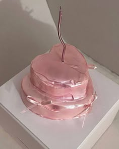 a pink cake sitting on top of a white box