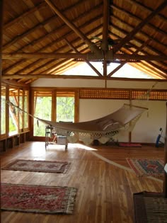 a hammock is in the middle of a room with wood floors and windows