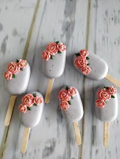 five pops with pink roses on them sitting on a table