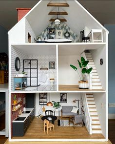 a doll house with white walls and wooden floors, stairs leading up to the second floor