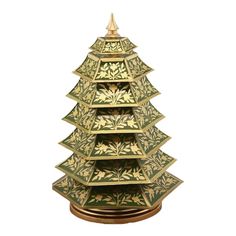 a decorative christmas tree made out of green and gold plates on a wooden stand with an ornament at the top