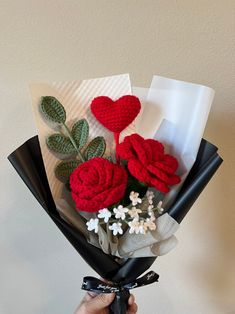 a hand holding a bouquet of flowers with hearts on it's back and two roses attached to the stems