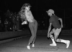 black and white photograph of two people playing with a frisbee in the street