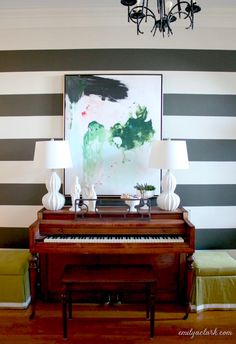 a living room with a piano and two lamps on the side table in front of it