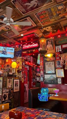 a room filled with lots of colorful signs and pictures on the walls, ceiling fans and tables