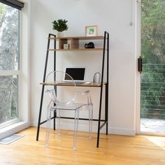 a desk with a laptop on it in front of a window and a wooden floor