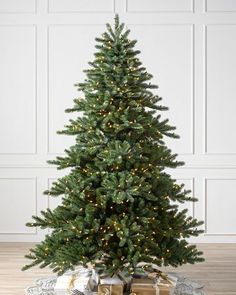 a small christmas tree with presents under it on the floor in front of a white wall