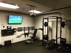 a home gym with equipment and a flat screen tv mounted on the wall above it